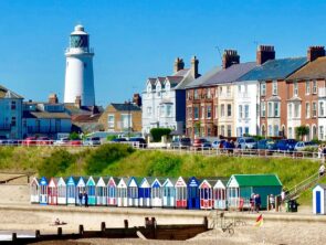 imagen de la playa de suffolk con casetas y un faro mirando al mar del programa junior de inglés y punto